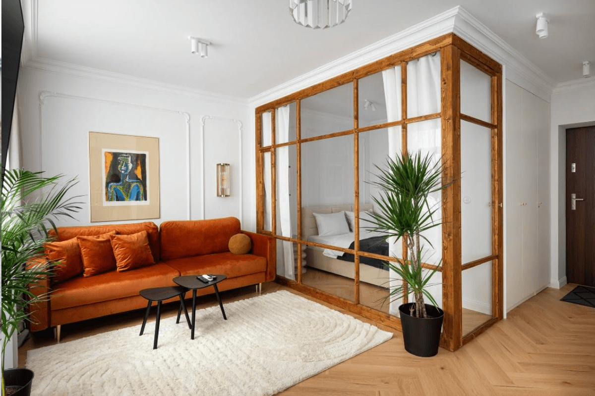Wnętrze salonu z eklektycznym i tradycyjnym stylem, pomarańczowa sofa, drewniana ścianka.