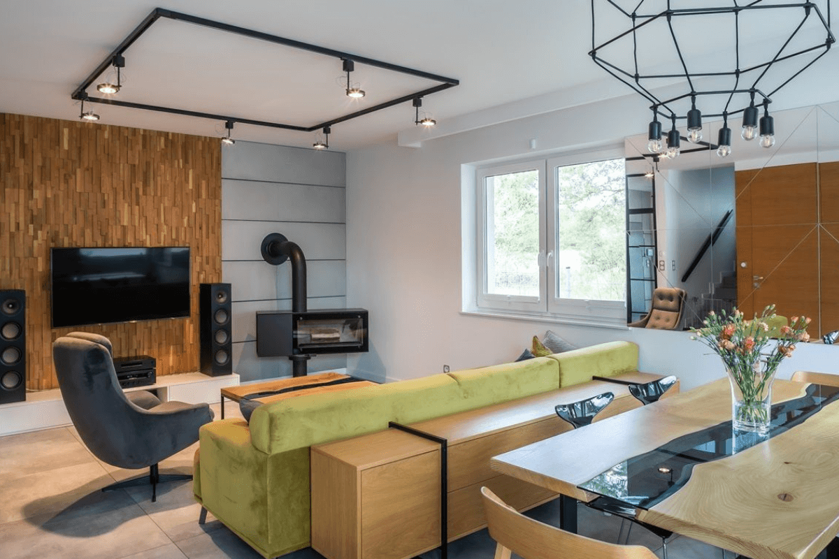 Wnętrze salonu w stylu industrialnym i minimalistycznym z drewnianą ścianą i szarymi meblami.