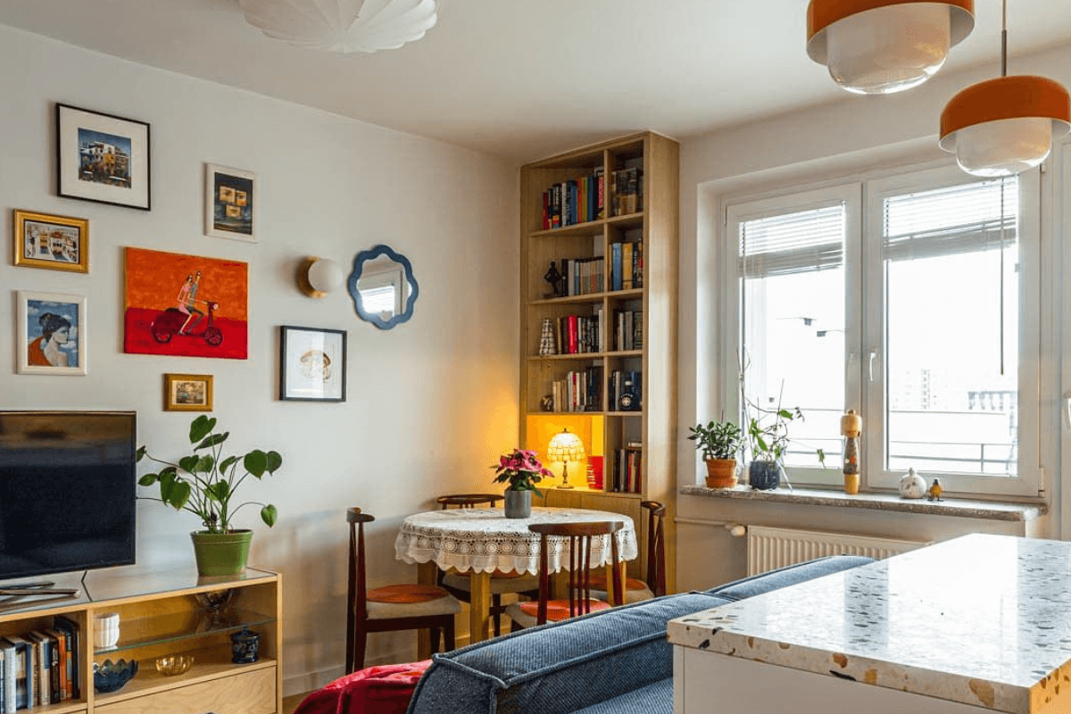 Wnętrze salonu z niebieską sofą, drewnianą półką, vintage i dopamine decor