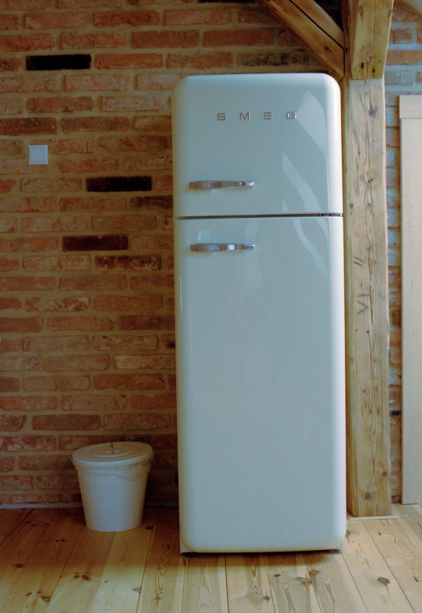 Miętowa lodówka retro SMEG na tle czerwonej cegły