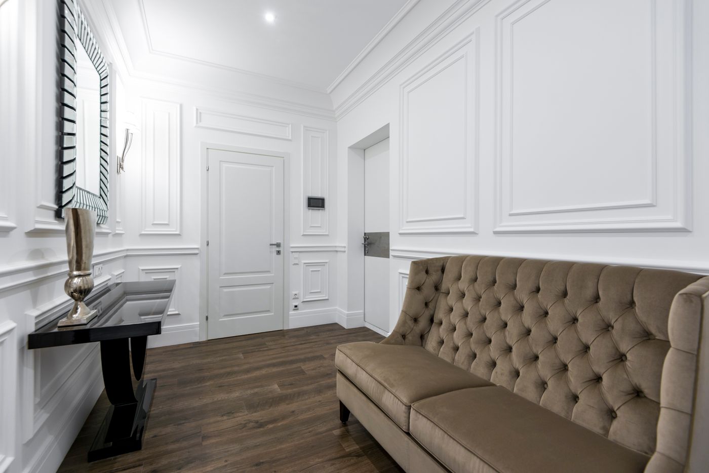 Biała boazeria ze sztukaterią panelową i pikowana sofa