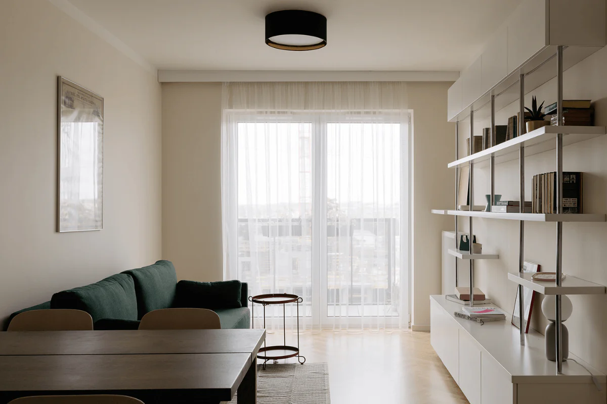 Wnętrze salonu w stylu minimalistycznym, nowoczesnym i skandynawskim z zieloną sofą.