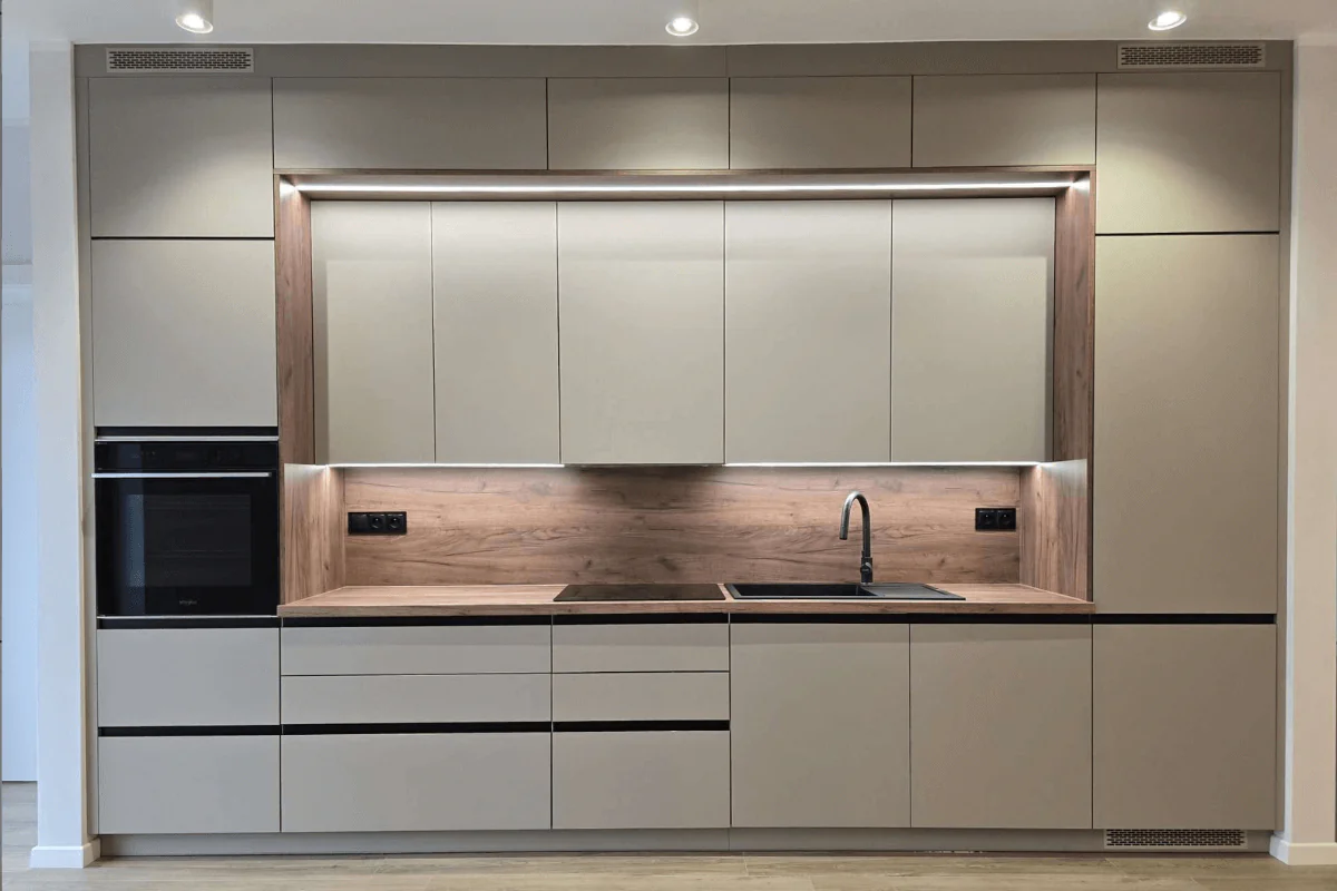 Współczesna kuchnia z szarymi meblami i drewnianym blatem, z nowoczesnym oświetleniem.