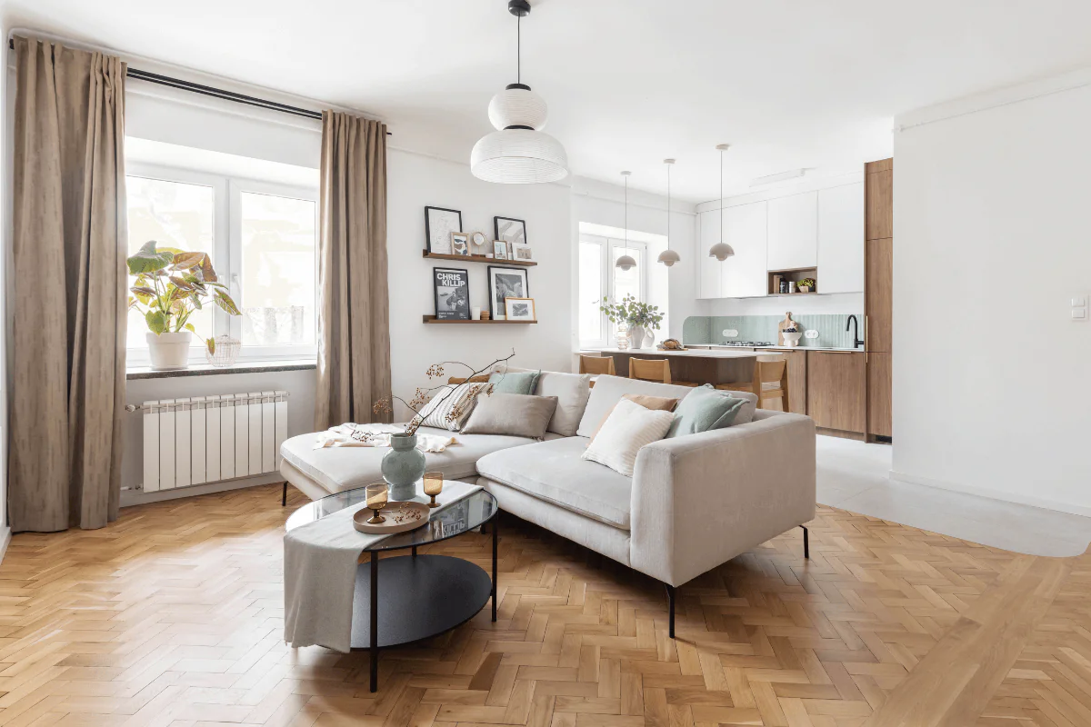 Wnętrze salonu w stylu art deco i skandynawskim z beżową sofą, drewnianym stołem i roślinnością.