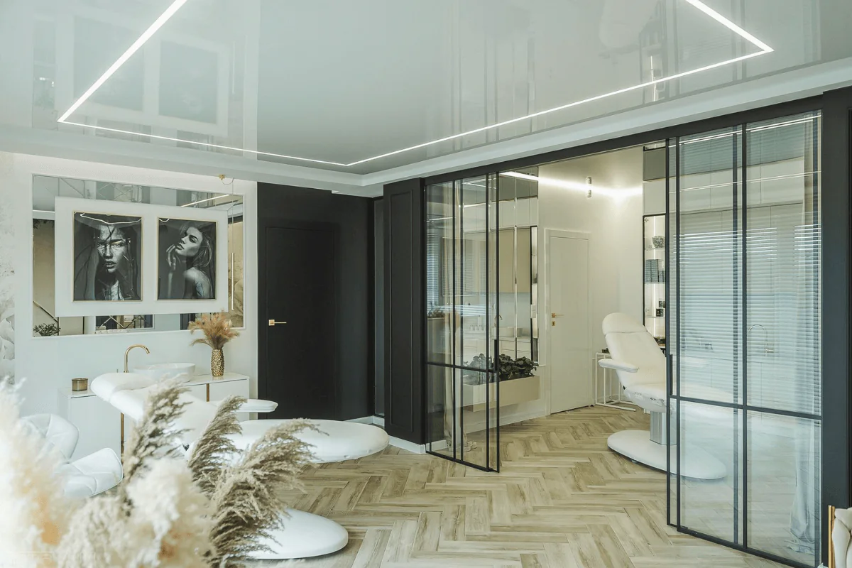 Wnętrze salonu kosmetycznego w stylu glamour z nowoczesnymi akcentami, biały stół i czarne ściany.