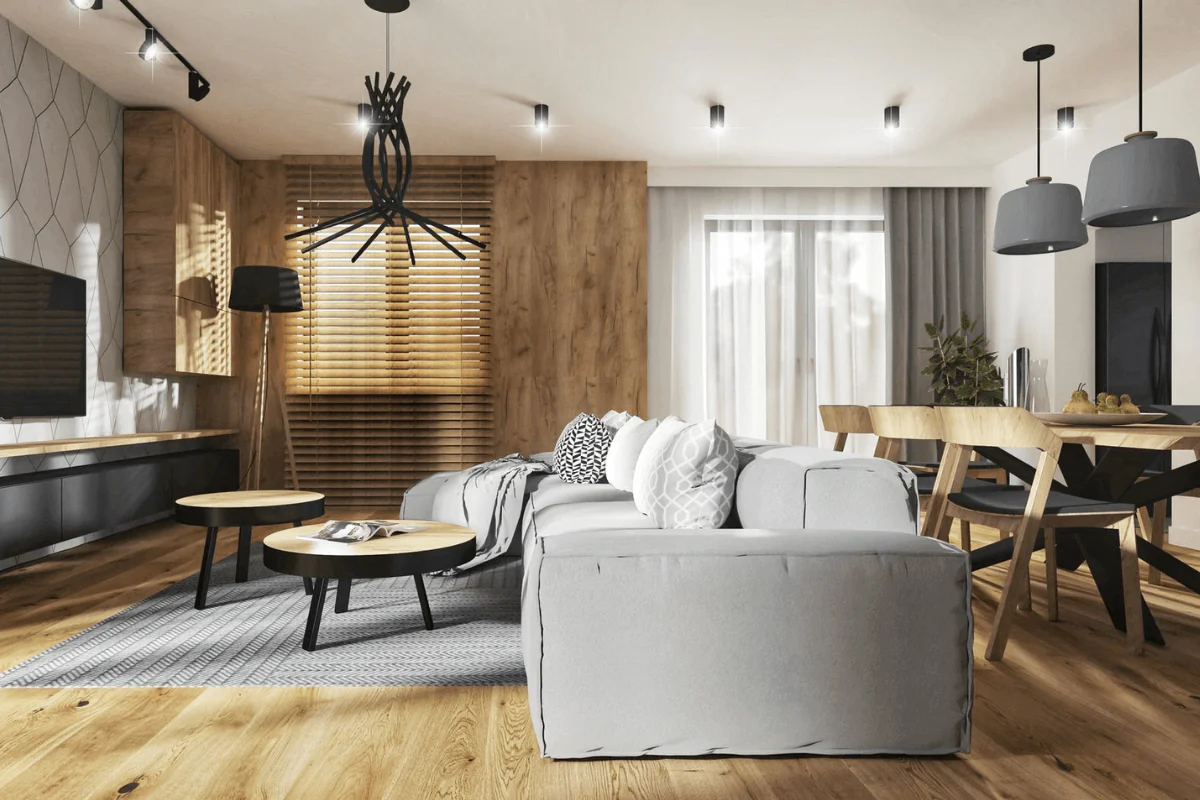 Wnętrze nowoczesnego salonu z szarym narożnikiem, drewnianymi meblami i dekoracjami skandynawskimi.