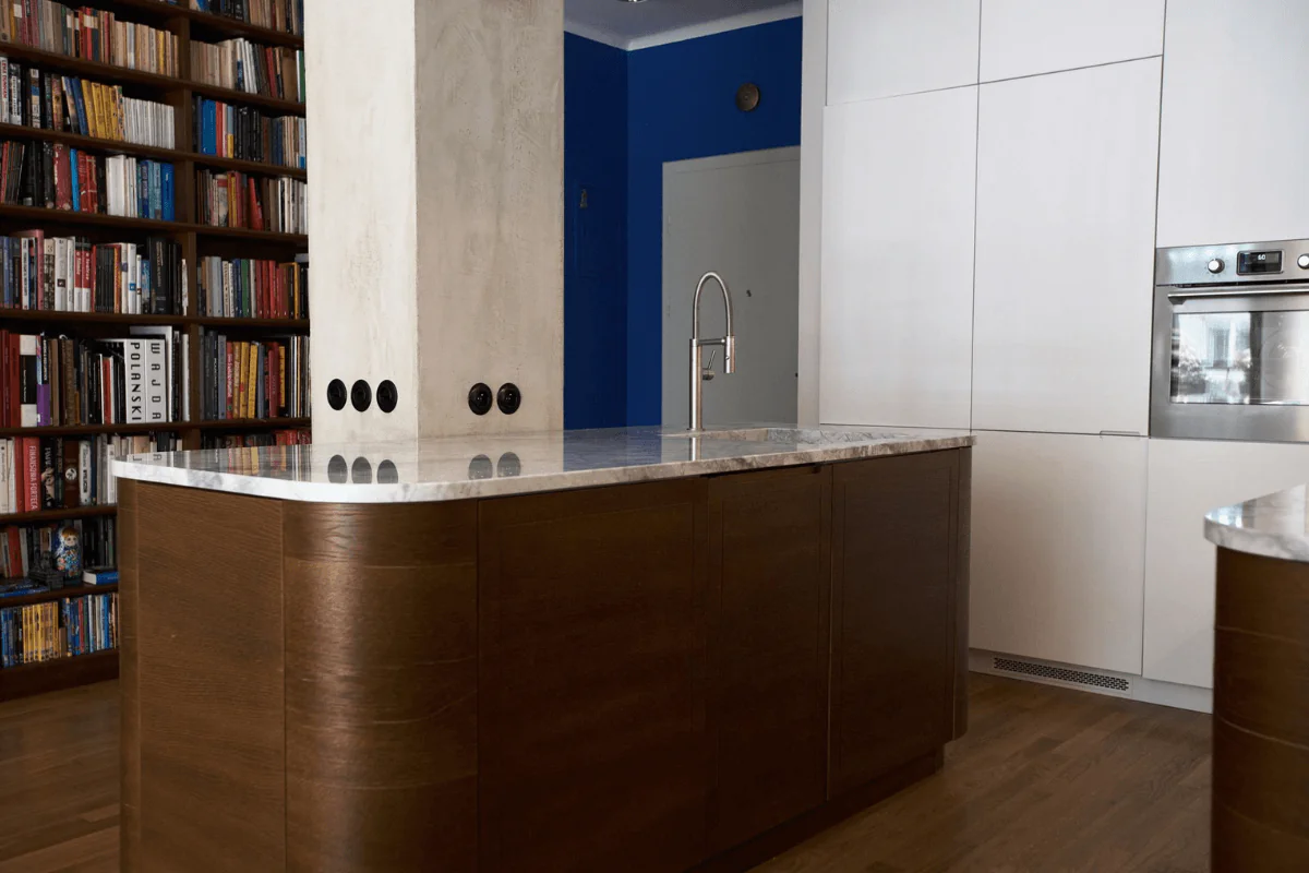 Eklektyczna kuchnia z brązowym blatem, białymi meblami i niebieską ścianą.