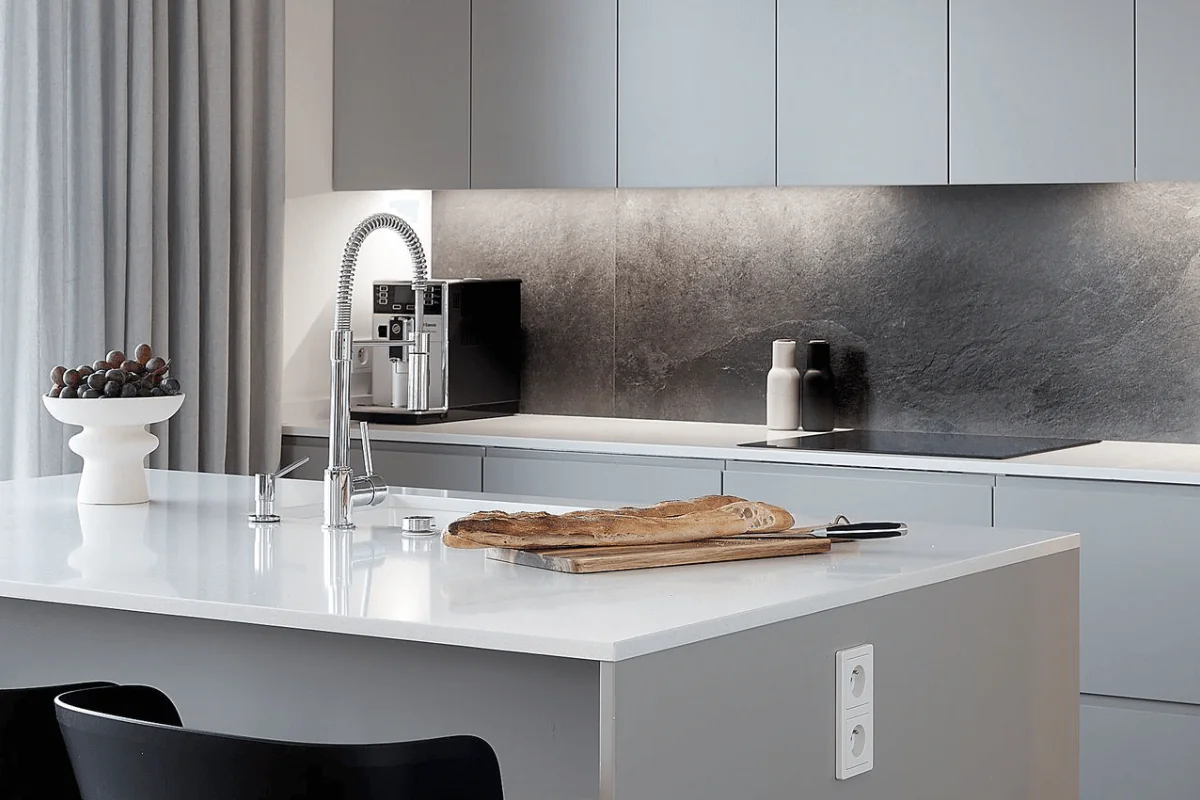 Wnętrze nowoczesnej kuchni z szarymi meblami i białym blatem, z dodatkami.