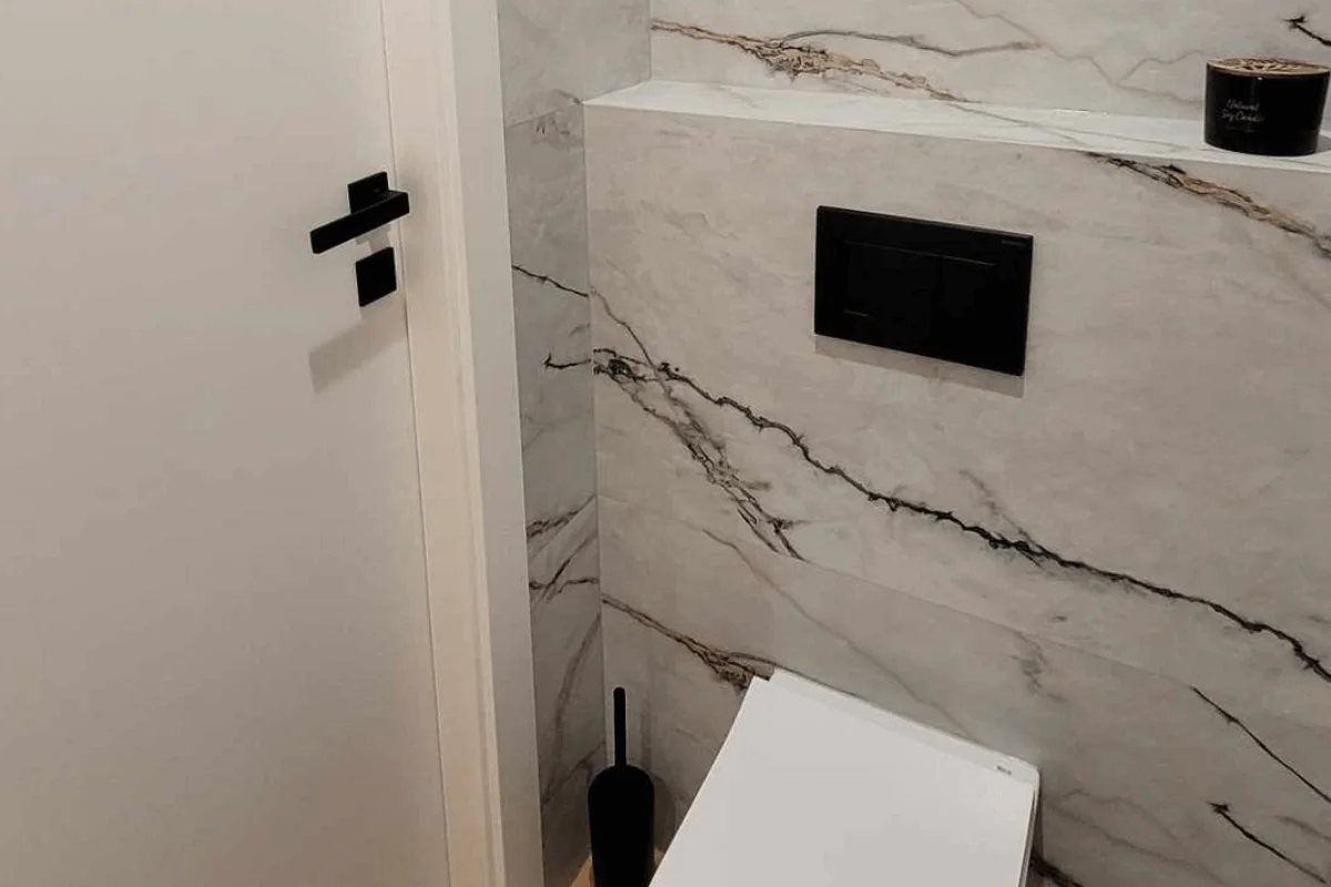 Minimalistyczna toaleta z białymi płytkami i drewnianą podłogą.