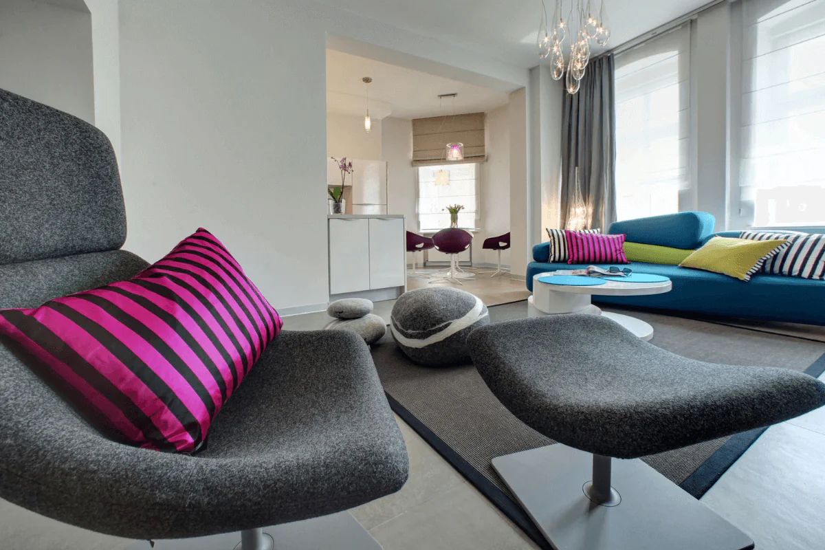 Wnętrze salonu z minimalistycznym wystrojem, niebieską sofą i różowymi akcentami.
