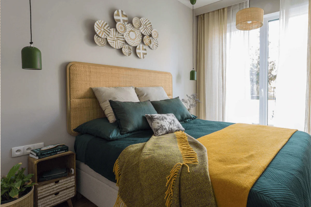 Sypialnia boho z zielonymi poduszkami i żółtym kocem, nowoczesne oświetlenie.