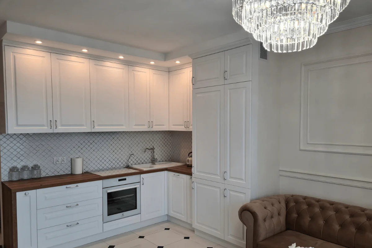 Kuchnia w stylu tradycyjnym z białymi meblami i drewnianym blatem.