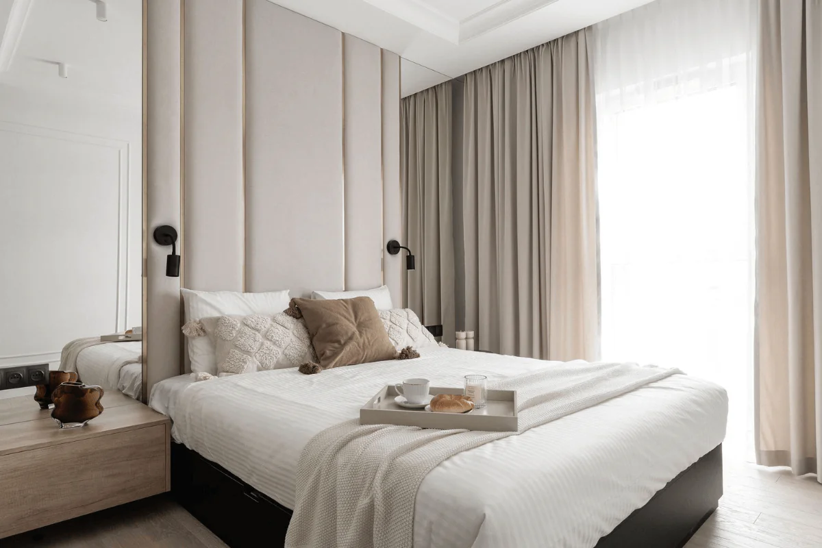 Współczesna sypialnia z jasnymi zasłonami i komfortowym łóżkiem.