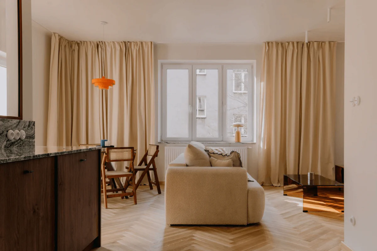 Wnętrze salonu w stylu quiet luxury, soft minimalizm i vintage z beżową sofą i drewnianymi akcentami.