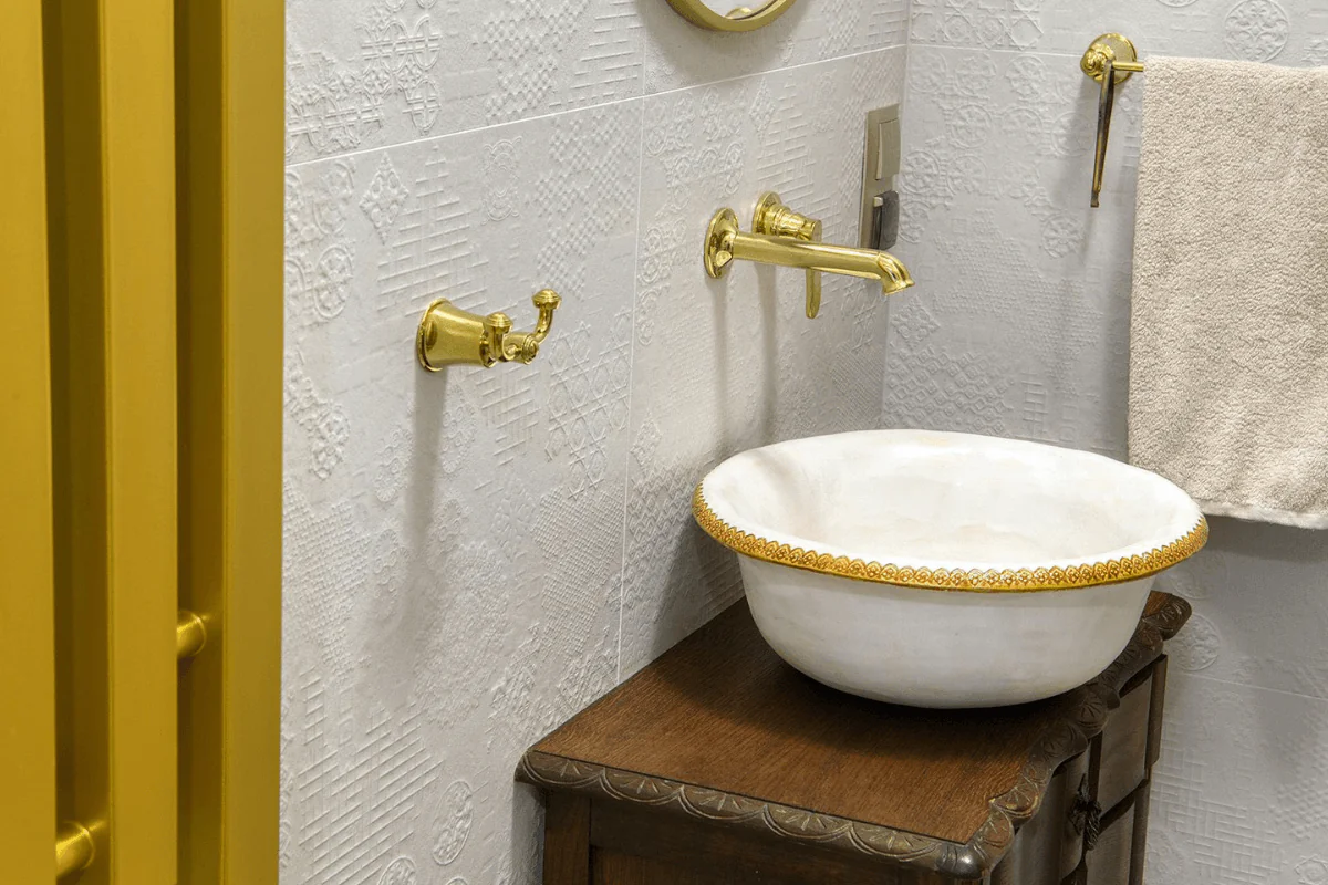 Wnętrze łazienki z umywalką, złotymi detalami i rustykalnym stylem.