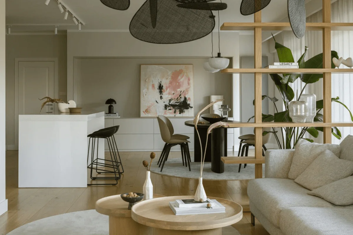 Wnętrze jadalni z białym stołem, drewnianymi krzesłami i nowoczesnym oświetleniem.