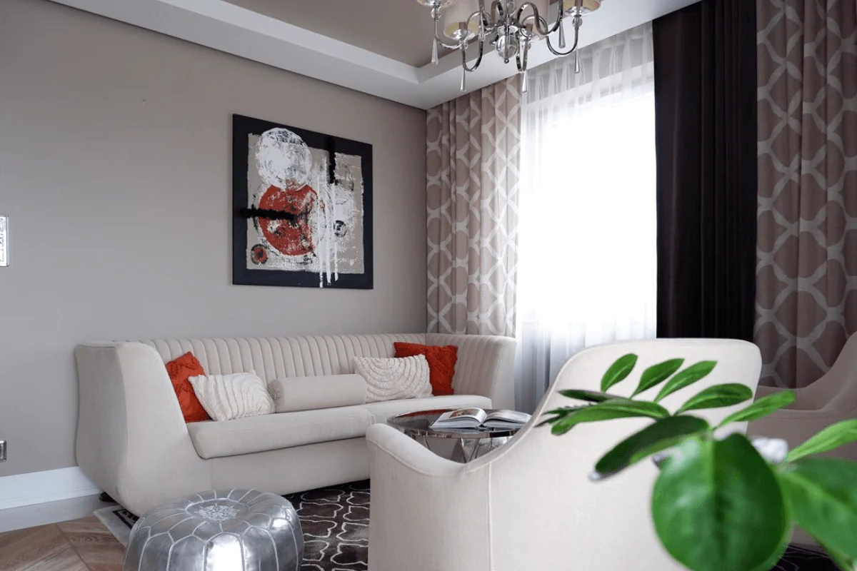 Nowoczesny salon z jasną sofą, czerwonymi poduszkami i dekoracyjnym obrazem. Styl tradycyjny.