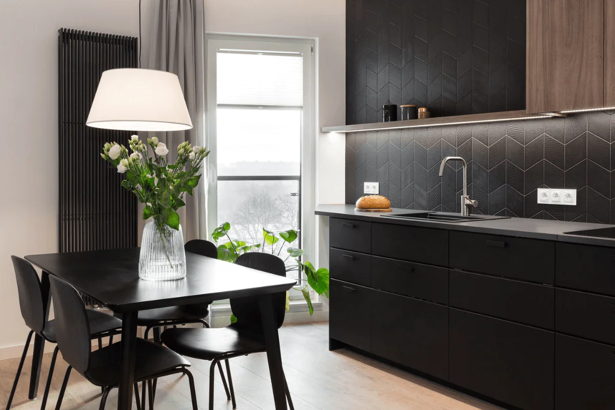 Wnętrze nowoczesnej kuchni z czarnymi meblami i drewnianym blatem.