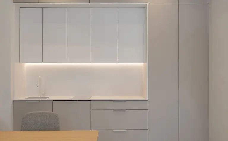 Biuro w stylu japandi i minimalistycznym z szarymi meblami i drewnianym biurkiem.