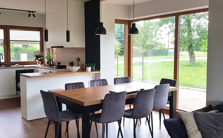 Nowoczesna kuchnia industrialna z drewnianym blatem i skandynawskimi krzesłami, okna z widokiem