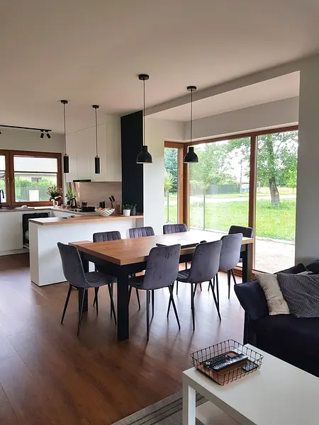 Nowoczesna kuchnia industrialna z drewnianym blatem i skandynawskimi krzesłami, okna z widokiem