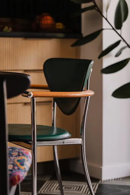 Wnętrze kuchni z zielonymi krzesłami i drewnianymi elementami, nowoczesny design.