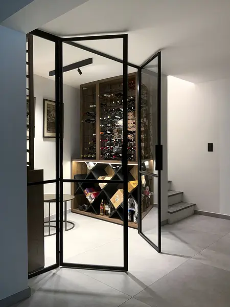 Przestrzeń z minimalistycznym regałem na wino i szklanymi drzwiami, styl minimaluxe i quiet luxury.
