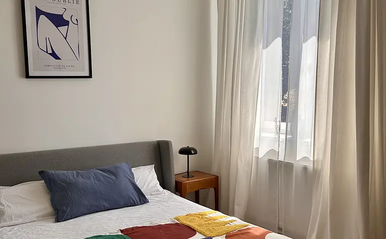 Sypialnia w stylu eklektycznym z kolorową pościelą i lampą.