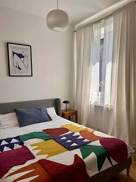 Sypialnia w stylu eklektycznym z kolorową pościelą i lampą.