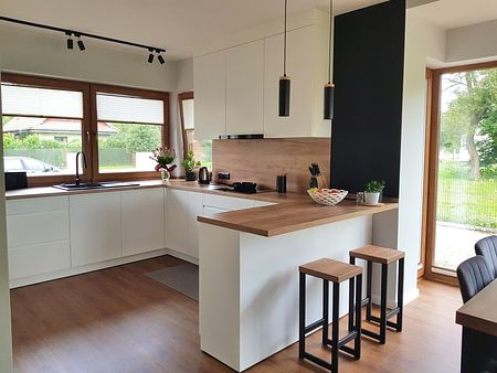 Kuchnia w stylu industrialnym i skandynawskim z białymi meblami i drewnianymi akcentami.