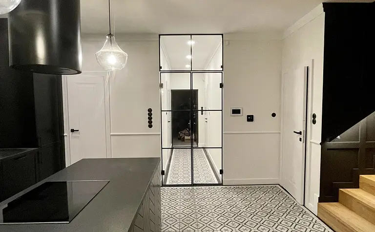 Wnętrze kuchni w stylu art deco z czarnymi meblami, industrialnymi akcentami i rustykalnymi detalami.
