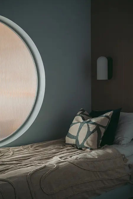 Sypialnia w stylu eklektycznym z nowoczesnym oknem i minimalistycznymi poduszkami.