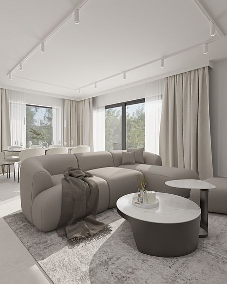 Wnętrze minimalistycznego salonu z szarym narożnikiem i białymi zasłonami.