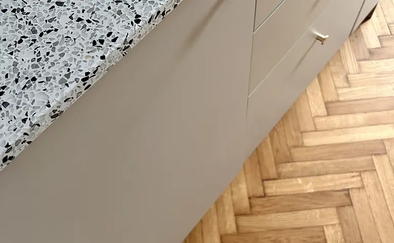 Wnętrze kuchni z szarym blatem, drewnianą podłogą w stylu eklektycznym, skandynawskim i vintage.