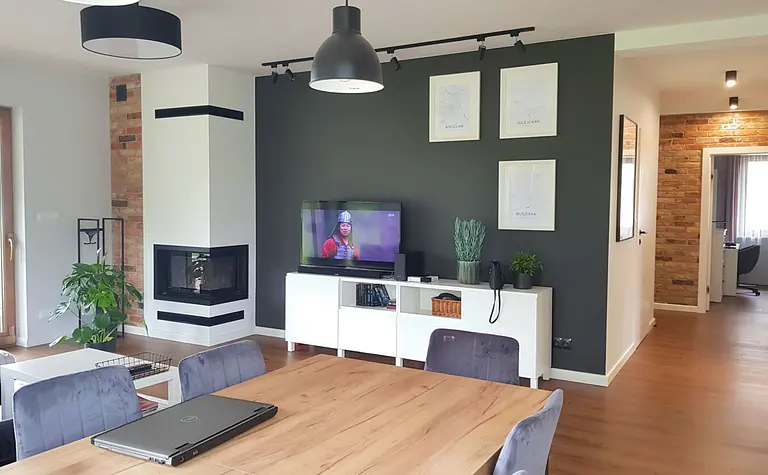 Nowoczesny salon z kominkiem, drewnianym stołem i szarymi akcentami w stylu industrialnym, skandynawskim i prowansalskim.