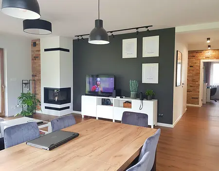 Nowoczesny salon z kominkiem, drewnianym stołem i szarymi akcentami w stylu industrialnym, skandynawskim i prowansalskim.