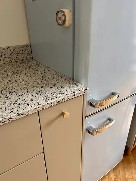 Kuchnia w stylu eklektycznym z błękitną lodówką i jasnymi szafkami, vintage wykończenie.