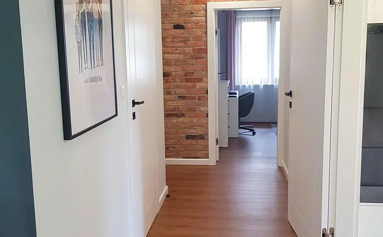 Przedpokój z białymi drzwiami, drewnianą podłogą i ceglaną ścianą w stylu industrialnym, nowoczesnym, prowansalskim i skandynawskim.