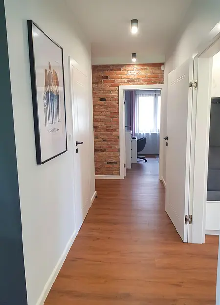 Przedpokój z białymi drzwiami, drewnianą podłogą i ceglaną ścianą w stylu industrialnym, nowoczesnym, prowansalskim i skandynawskim.