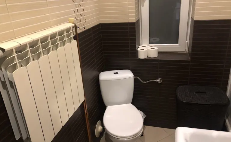 Łazienka z białą toaletą, brązowymi płytkami i minimalistycznym designem.