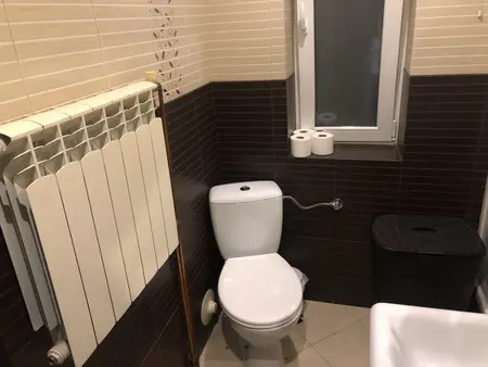 Łazienka z białą toaletą, brązowymi płytkami i minimalistycznym designem.