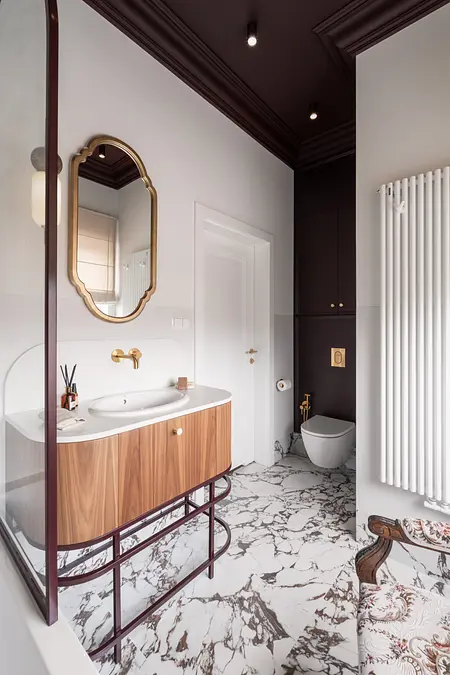 Wnętrze łazienki z eklektycznymi i vintage akcentami, drewniana szafka, marmurowa posadzka.