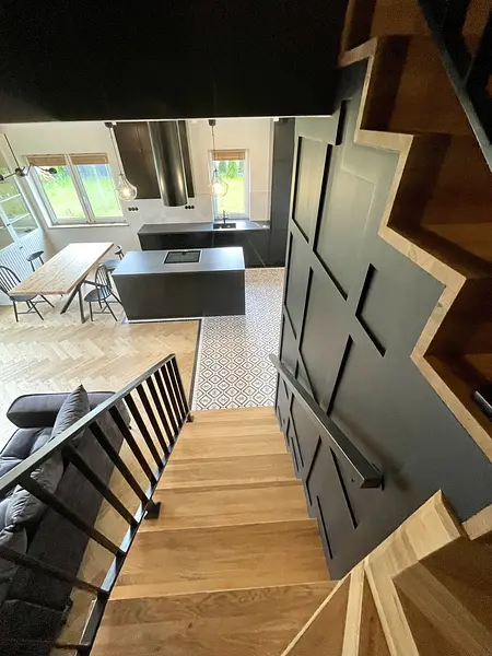 Wnętrze kuchni w stylu industrialnym z czarnymi meblami i drewnianymi akcentami.