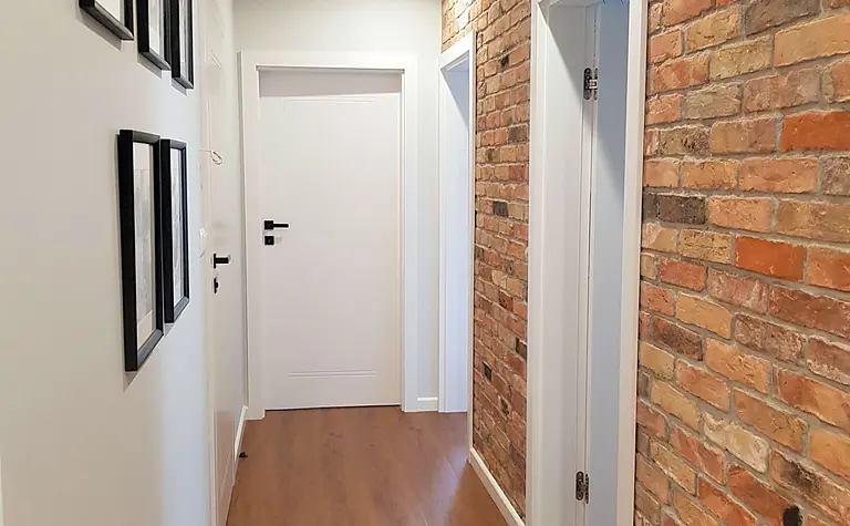 Przedpokój w stylu industrialnym z ceglaną ścianą i nowoczesnym oświetleniem