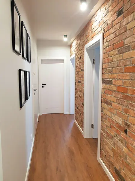 Przedpokój w stylu industrialnym z ceglaną ścianą i nowoczesnym oświetleniem