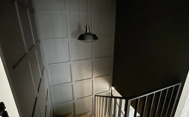 Schody w stylu rustykalnym z czarną balustradą i drewnianymi detalami.