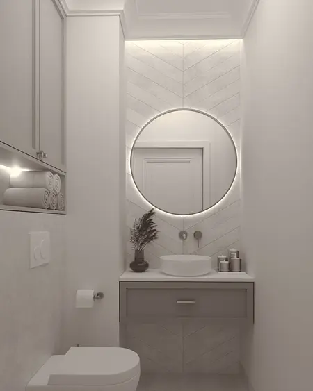 Nowoczesna łazienka z okrągłym lustrem, jasnymi płytkami i eleganckim umywalką w stylu quiet luxury.
