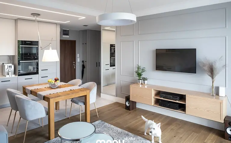 Nowoczesne wnętrze z drewnianym stołem, szarymi meblami, elementami art deco, quiet luxury i tradycyjnymi akcentami.