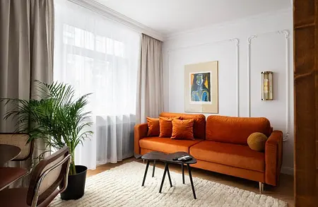 Wnętrze salonu z eklektycznym stylem, pomarańczowa sofa, rośliny i nowoczesne akcenty