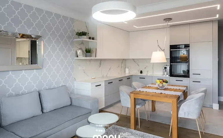 Wnętrze kuchni z szarymi meblami, drewnianym stołem oraz elementami art deco, nowoczesnym i tradycyjnym.
